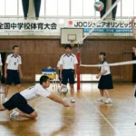 中学校の体育館でバレーボールのレシーブ練習をする男女の生徒たち