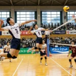 全日本大学バレーボールの試合シーン。背番号3番と6番の選手が同時にジャンプしてスパイクを狙う、同時多発位置差攻撃(シンクロ攻撃)のパターン。ネット際で対峙する3枚のブロック。