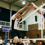 バレーボールのブロック技術：ネット際で高くジャンプし、両腕を真っ直ぐに伸ばして相手の攻撃を防ぐ選手の理想的なフォーム