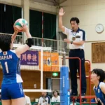 バレーボールの反則やルールを判定する主審とネット際でトスを上げるセッターのプレー風景