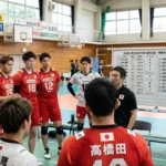 2026年バレーボール男子日本代表(龍神NIPPON)の練習風景。石川祐希選手や高橋藍選手ら主力メンバーがコーチを囲み、戦略を確認する様子。背景には選手名、背番号、身長が記載された2026年度版の選手名鑑ホワイトボードが設置されている。