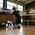 バレーボールのジャンプサーブを打つ瞬間の男子選手。体育館のコートで高くジャンプし、ネット越しにレシーブを構える相手チームに向かってサーブを放つダイナミックなフォーム。